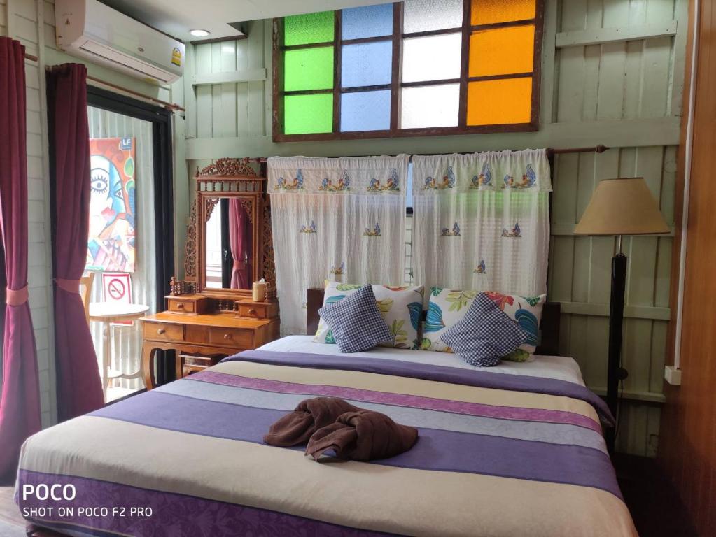 um quarto com uma cama grande e janelas coloridas em tamarind guesthouse em Phra Nakhon Si Ayutthaya