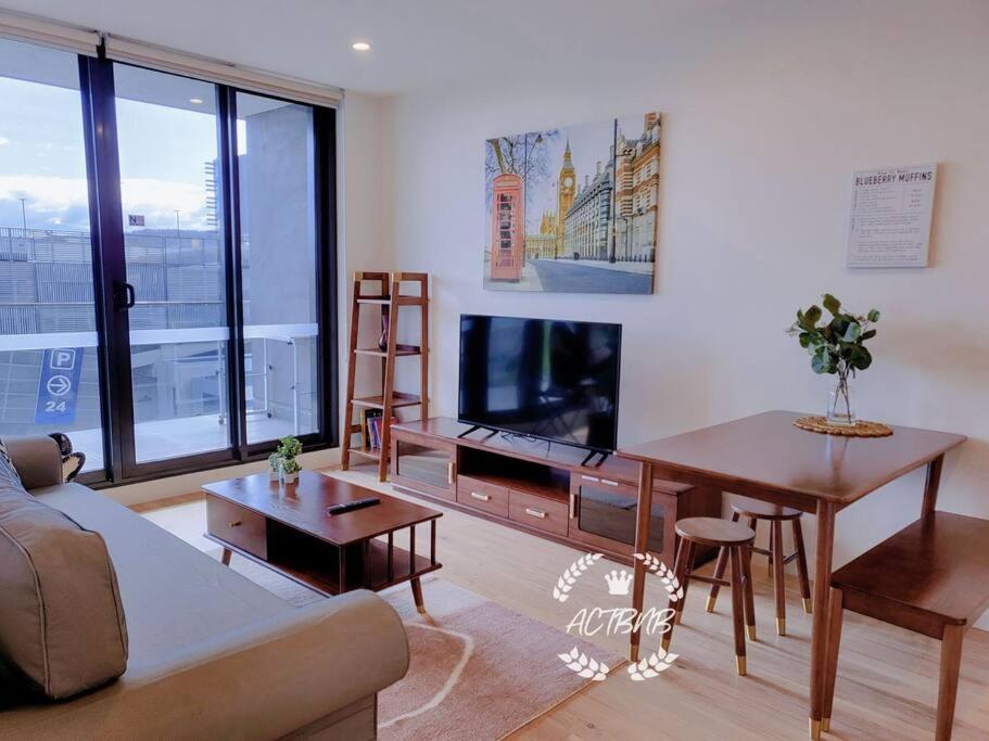 a living room with a couch and a table and a tv at City View Lovely 1BD Apartment @ CBD in Canberra