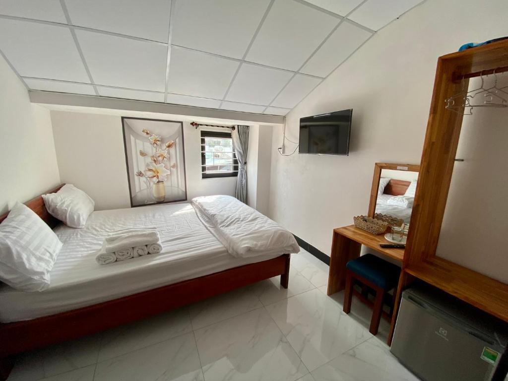 Dormitorio pequeño con cama y TV en BOBE Homestay en Hoi An