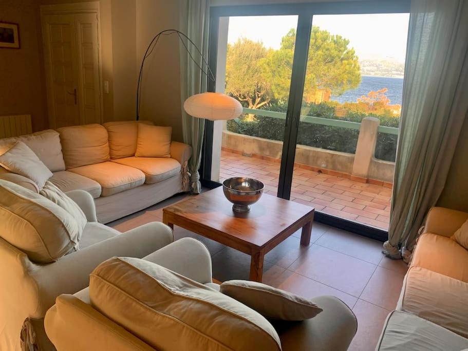 salon z kanapami i stołem oraz dużym oknem w obiekcie villa d'exception avec piscine , au bord de la mer w Hyères