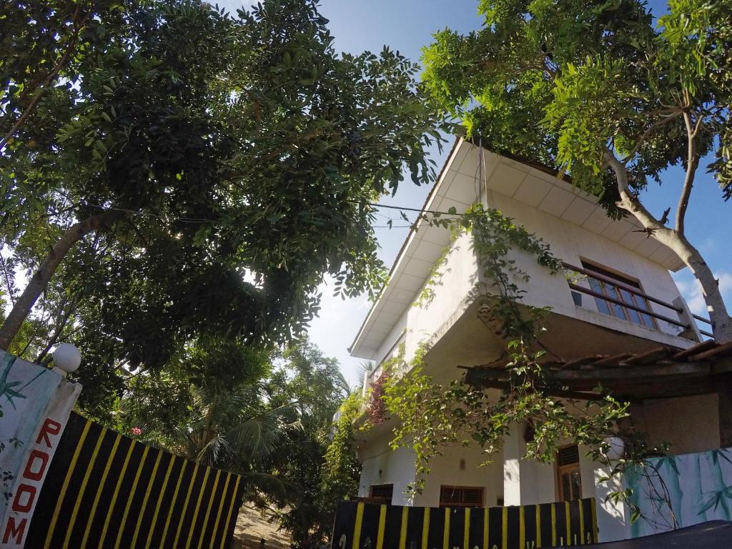 biały budynek z drzewami przed nim w obiekcie 20 House Villa w mieście Arugam Bay