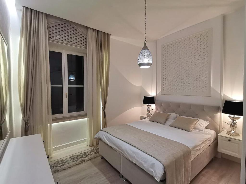 um quarto branco com uma cama e uma janela em Metropolis em Saraievo