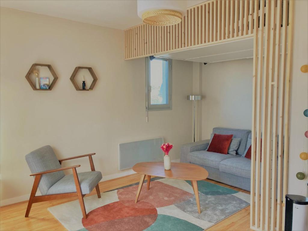 a living room with a couch and a table at Studio proche plage balcon et parking in Deauville