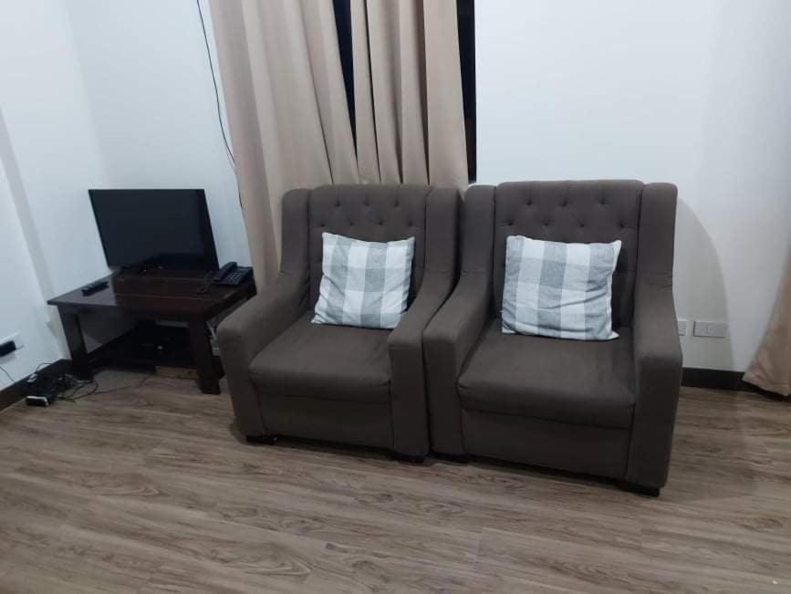 um sofá castanho com duas almofadas brancas e uma mesa em Edrose Condo Unit Rental em Baguio
