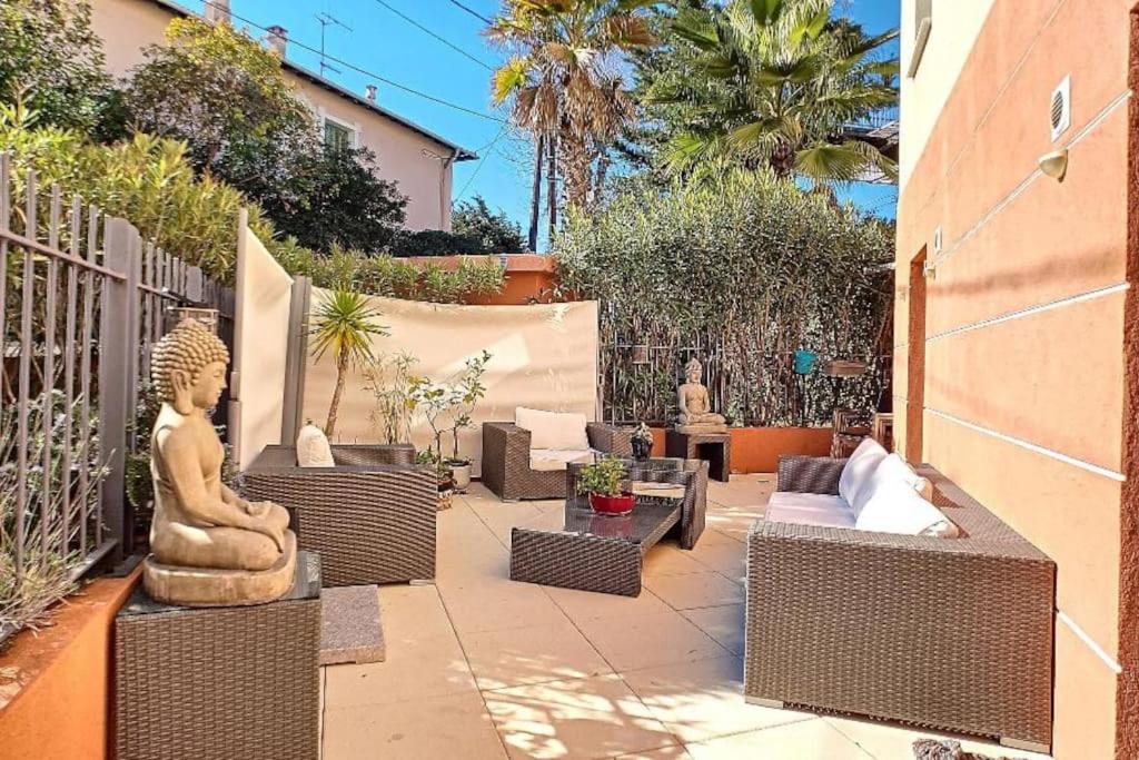 une terrasse avec de nombreuses chaises en osier et une statue. dans l'établissement Proche mer 3P+40m2 terrasse, à Antibes