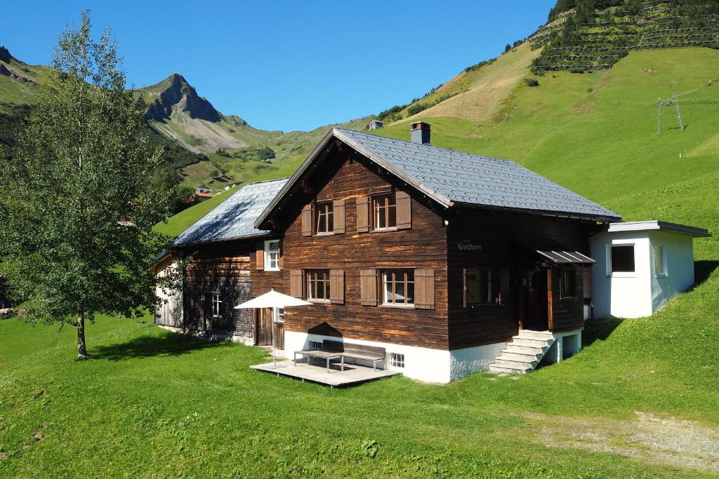 a wooden house on a hill with green grass at Haus Glatthorn in Faschina