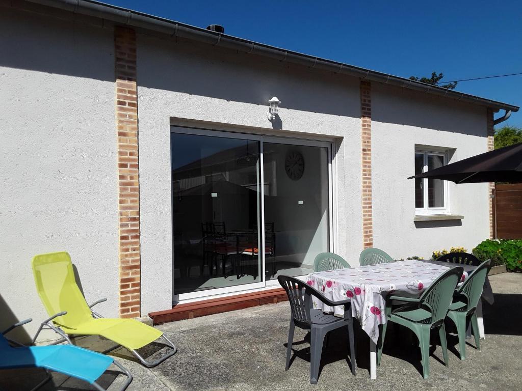 een patio met een tafel en stoelen voor een gebouw bij Maison plain pied a 10 mn de la plage en campagne in Saint-Malo