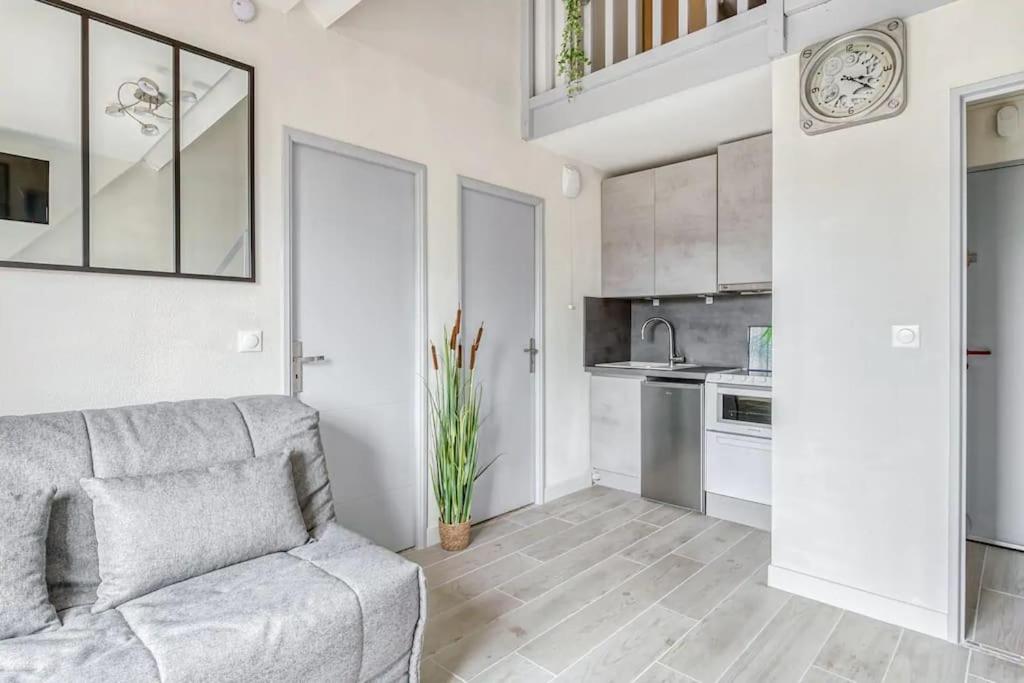 un salon avec un canapé et une cuisine dans l'établissement Cabourg Emeraude 2 étoiles plage et thalasso 100m parking gratuit, à Cabourg