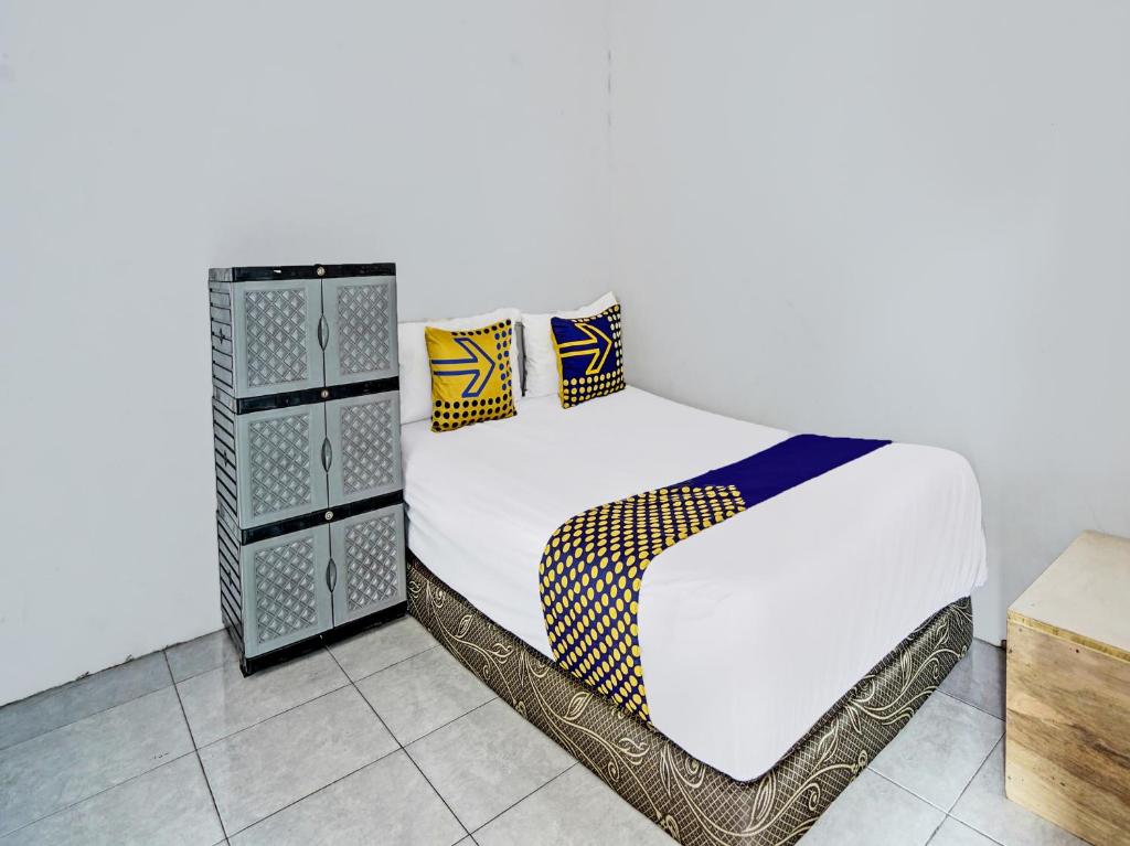 1 cama con sábanas blancas y almohadas en una habitación en OYO 92086 Fun Guesthouse Syariah, en Mojokerto