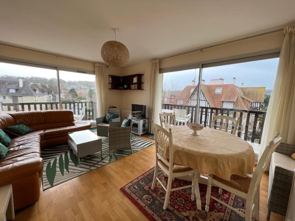 ein Wohnzimmer mit einem Tisch und einem Sofa in der Unterkunft La Vigie spacieux, lumineux, piscine in Deauville