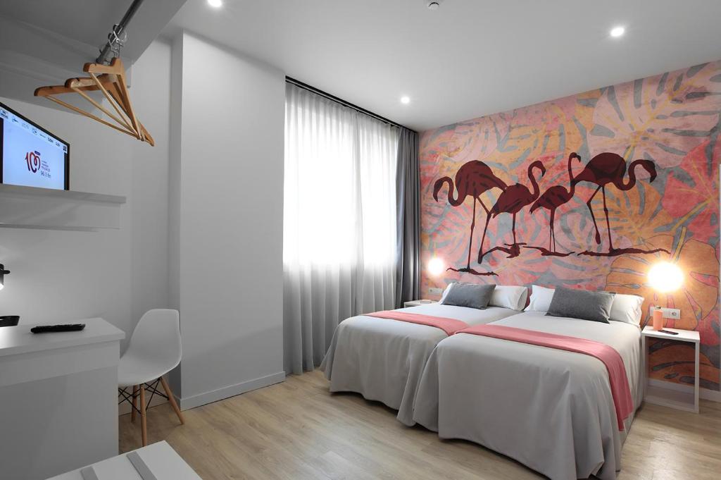 1 dormitorio con 1 cama grande y una pintura de flamencos en Eibarooms, en Éibar