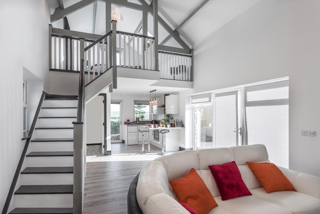 uma sala de estar com um sofá branco e uma escada em Curragh House Lodges em Kinsale