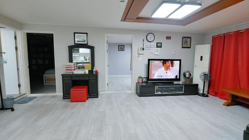 a living room with a television and a red curtain at The house of gallery in Daegu