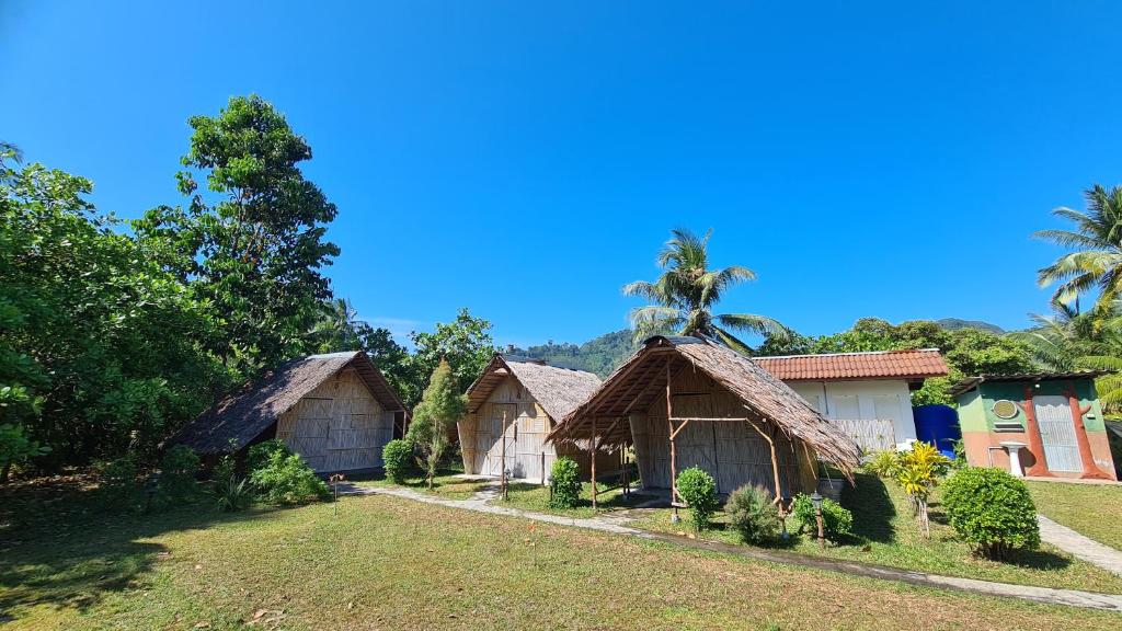 un groupe de bungalows avec des palmiers en arrière-plan dans l'établissement koh mook oyoy reggaebar bungalow, à Ko Muk
