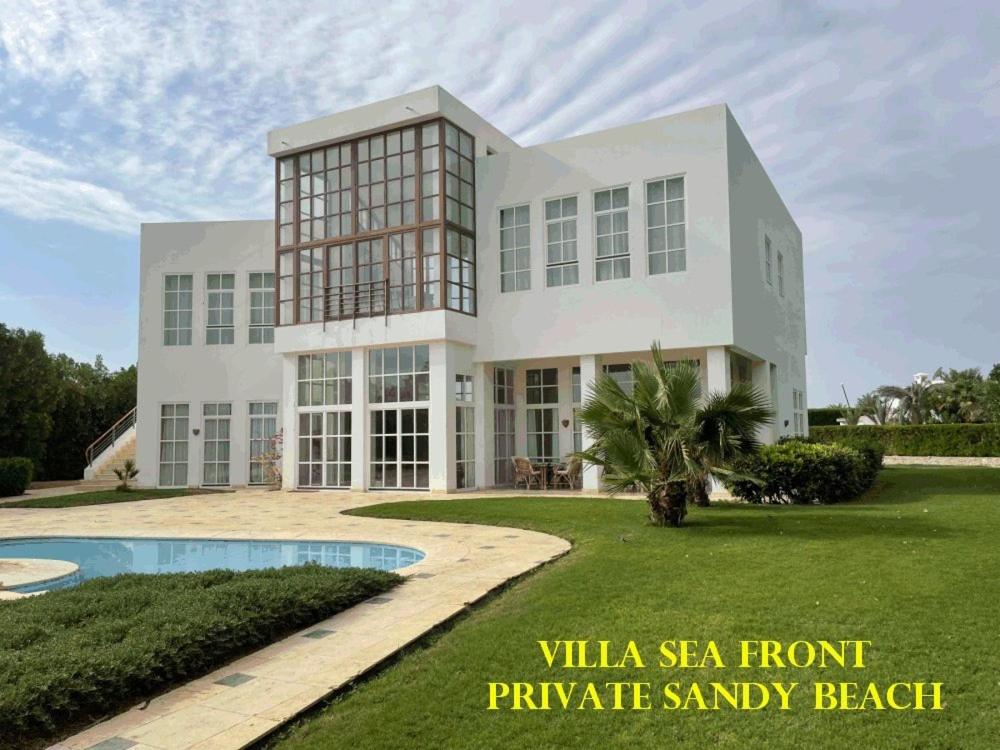 - un grand bâtiment blanc avec une piscine en face dans l'établissement El Gouna dream villa sea front max13+3 people, à Hurghada