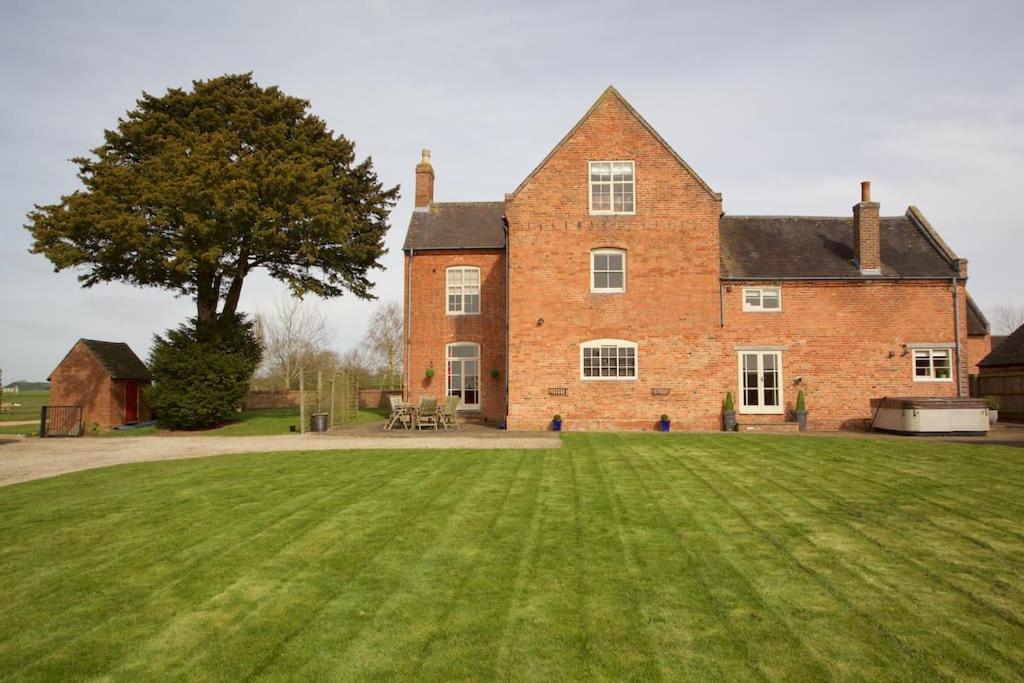 a large brick house with a large grass yard at Dunnimere Farm stay with Hot Tub - up to 20 in Haselour