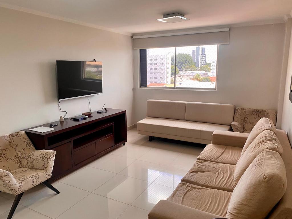 a living room with a couch and a flat screen tv at Apartamento perfeito, bem localizado, confortável, espaçoso e com bom preço insta thiagojacomo in Goiânia