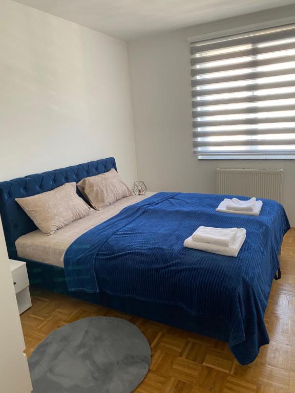 sypialnia z niebieskim łóżkiem i ręcznikami w obiekcie Apartman Nova Pale w mieście Pale