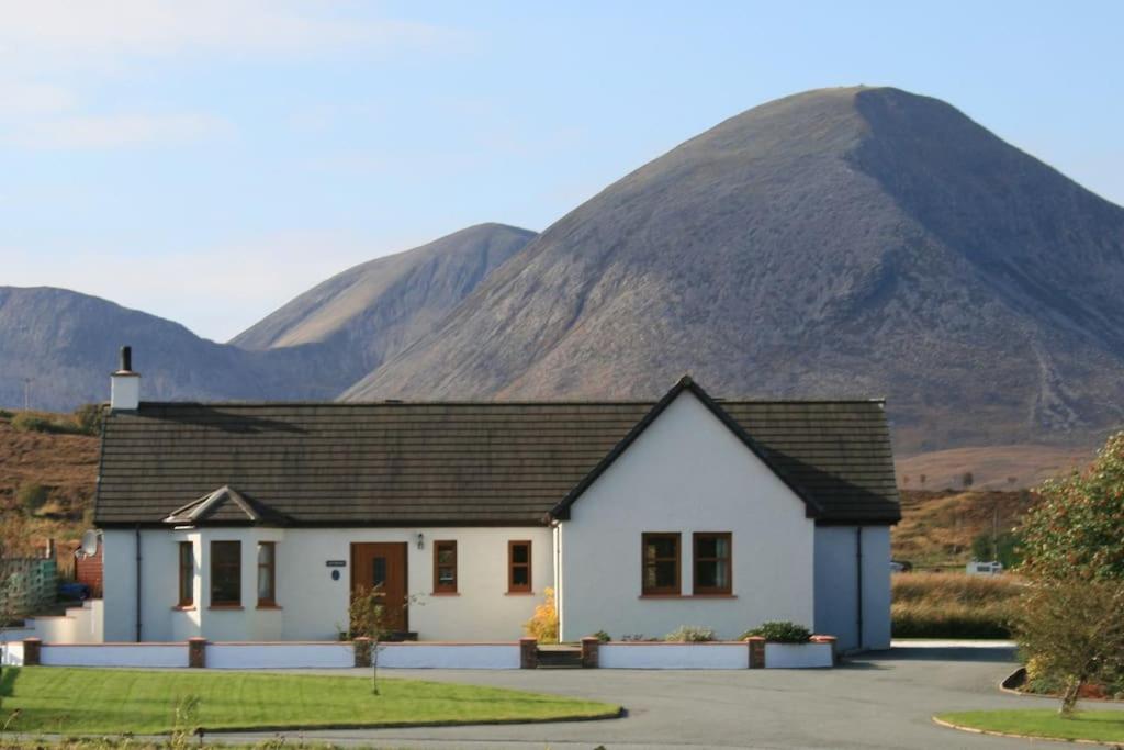 a white house with a mountain in the background at Ardmore luxury self catering cottage in Broadford
