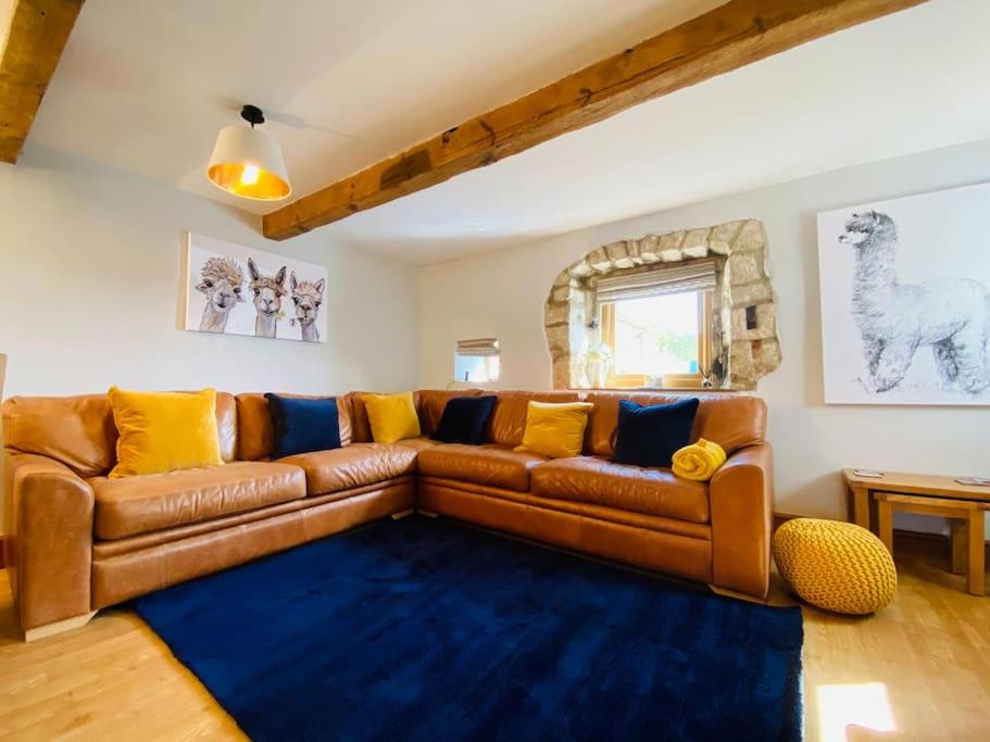 a living room with a brown leather couch and a blue rug at Rustic Retreats: Owslow Cottage with hot tub & Alpaca Walking Experiences in Carsington