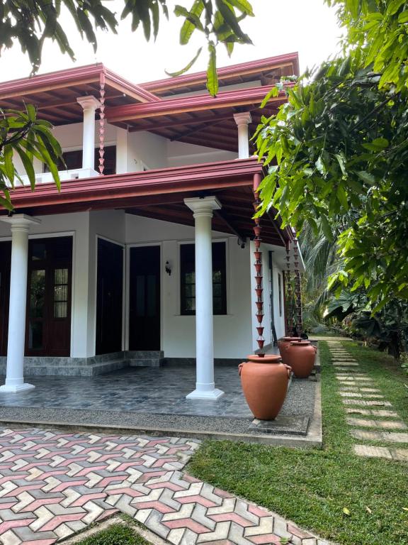 una casa con pilares y plantas delante de ella en Kalpa Place Hiriketiya, en Hiriketiya