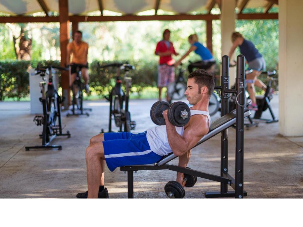 a man is doing a barbell deadlift in a gym at Calaserena Resort in Geremèas