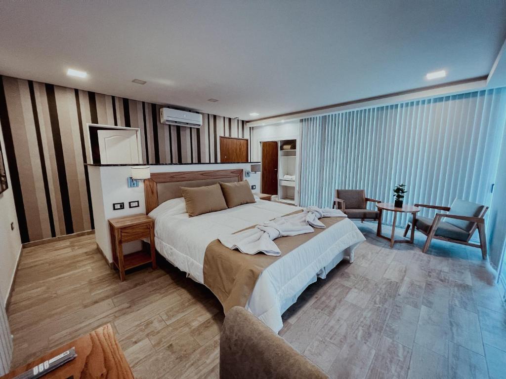 een slaapkamer met een groot bed en een woonkamer bij Altos de Los Paraísos Vista al lago y sierras in Juana Koslay 