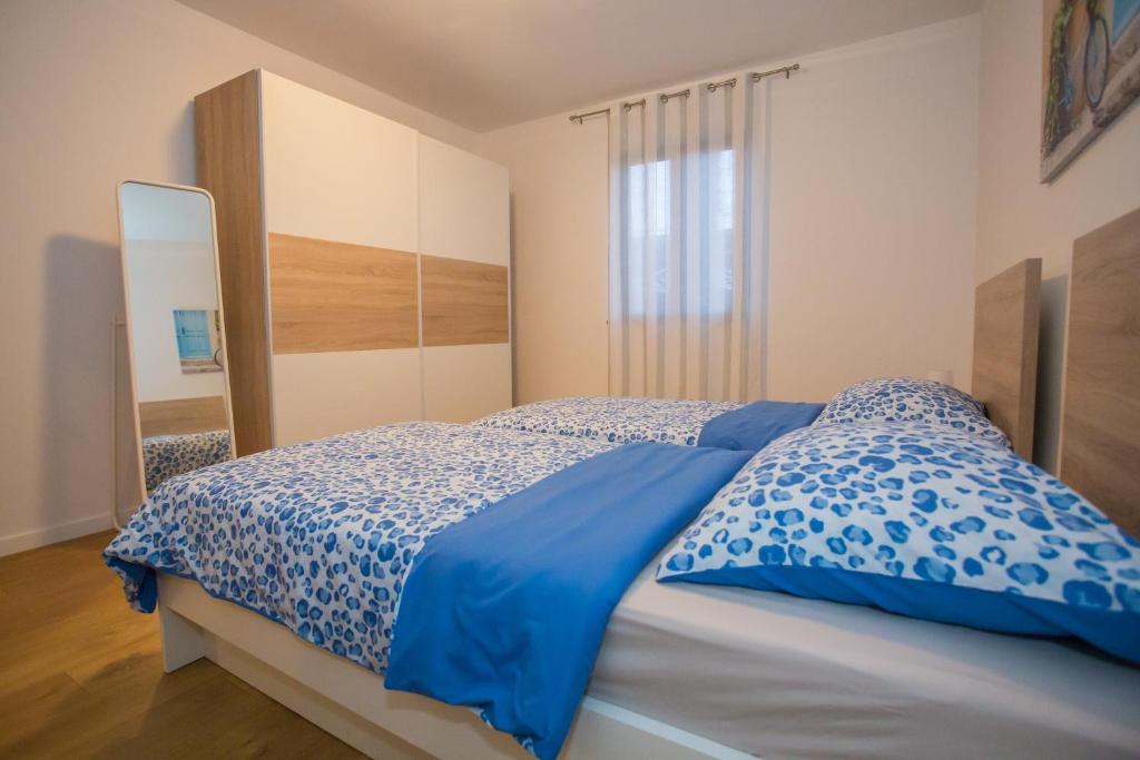 a bedroom with a bed with blue sheets and a mirror at Apartment Ivan 2 in Funtana