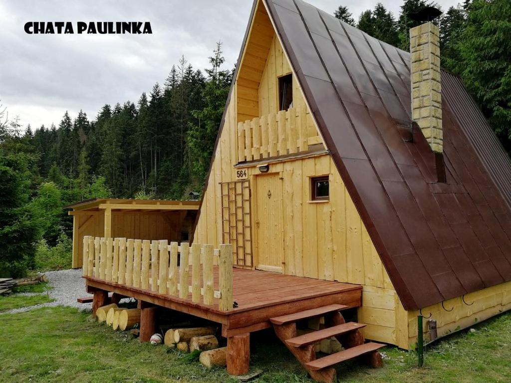a house with a bench and a pitched roof at Chata Zuzka pod Babou horou in Oravská Polhora