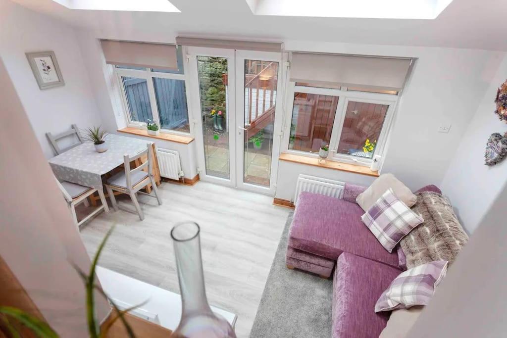 阿什伯恩的住宿－Cosy Heather Cottage，客厅配有紫色沙发和桌子