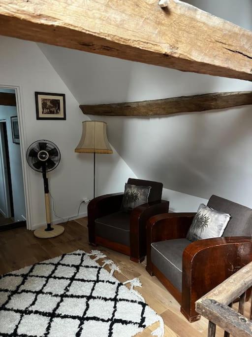 a living room with two couches and a fan at Gîte des 3 Marchands in Buzançais