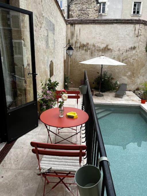 a patio with a table and chairs next to a pool at Gîte des 3 Marchands in Buzançais