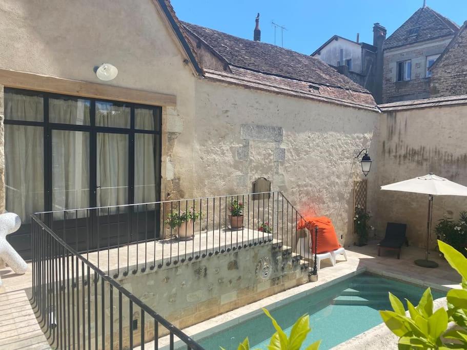 a person sitting next to a house with a swimming pool at Gîte des 3 Marchands in Buzançais