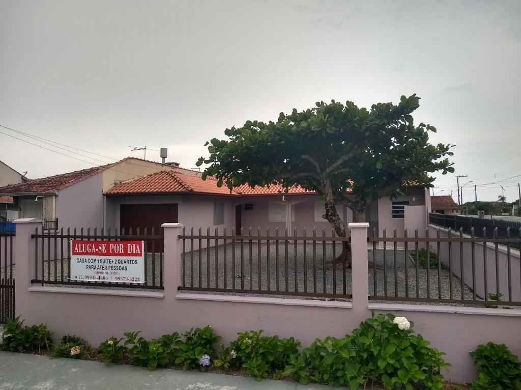 Una casa con una valla con un cartel. en Casa ampla a 50metros do mar, en Balneário Barra do Sul