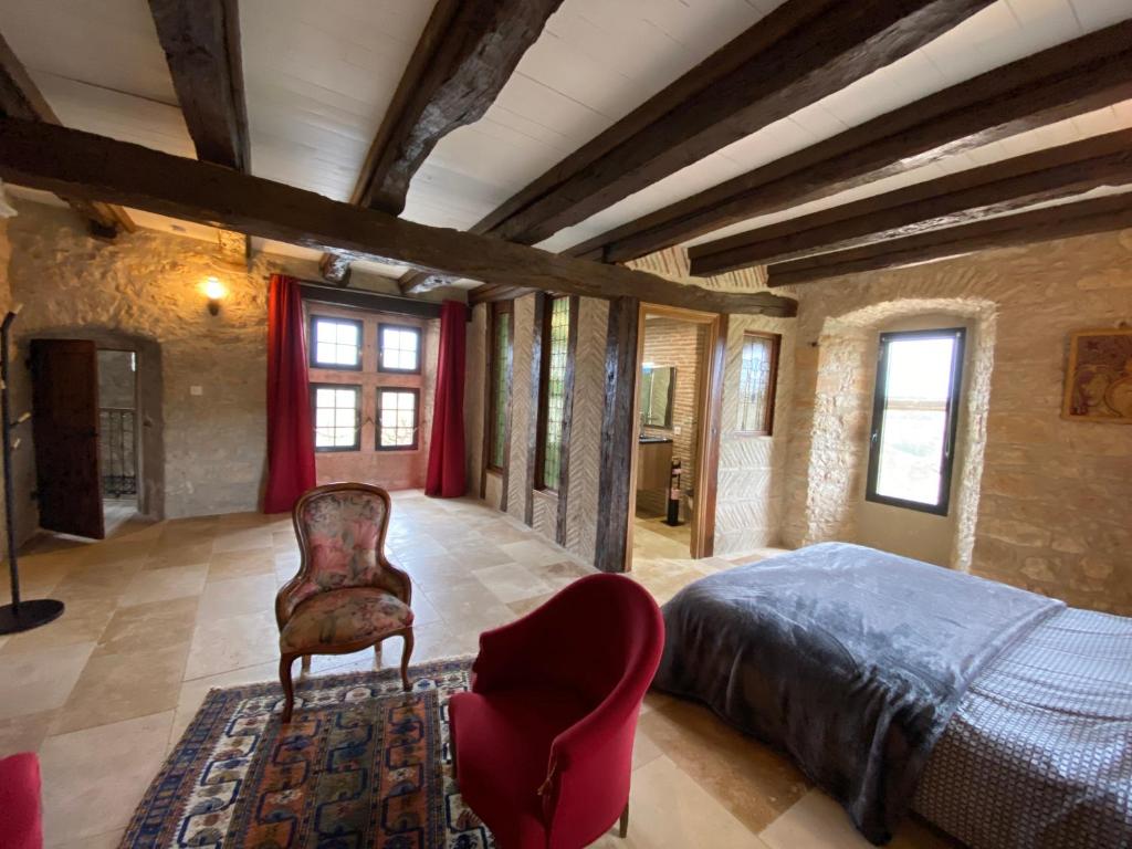 sypialnia z łóżkiem i krzesłem w obiekcie Maison de village, charme et confort w mieście Mauroux