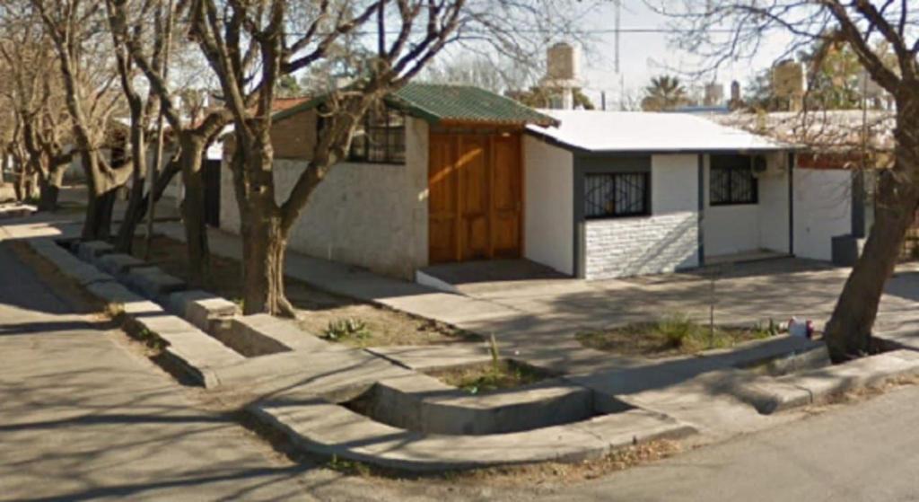 una pequeña casa blanca con una puerta marrón y árboles en Casa Alojamiento San Rafael en San Rafael