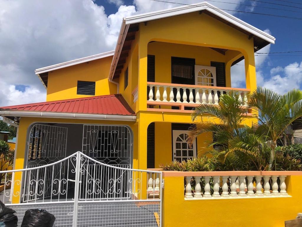 a yellow house with a white fence in front of it at DonaMae 2 story Barbados House in Bridgetown