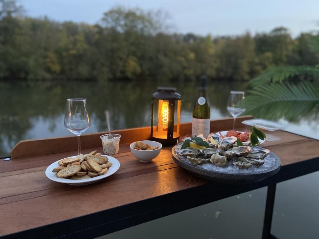 una mesa con dos platos de comida y una botella de vino en Studio sur la péniche Santa Julia à Chantilly Insolys en Saint-Leu-dʼEsserent