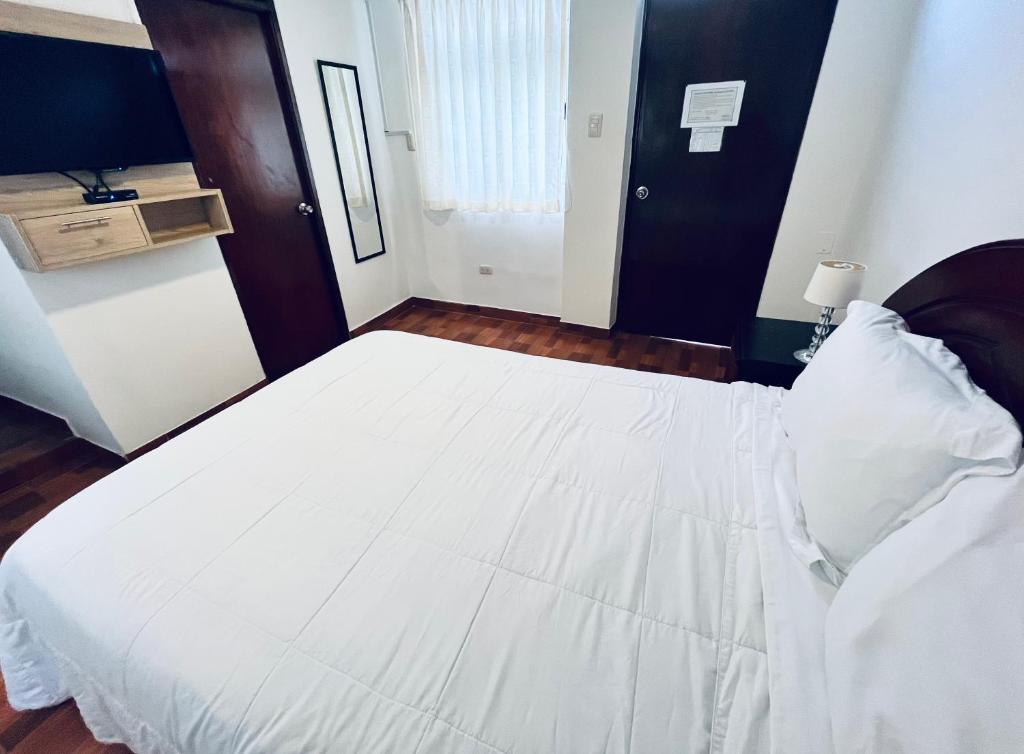 1 cama blanca grande en una habitación con TV en Casablanca Lima, en Lima