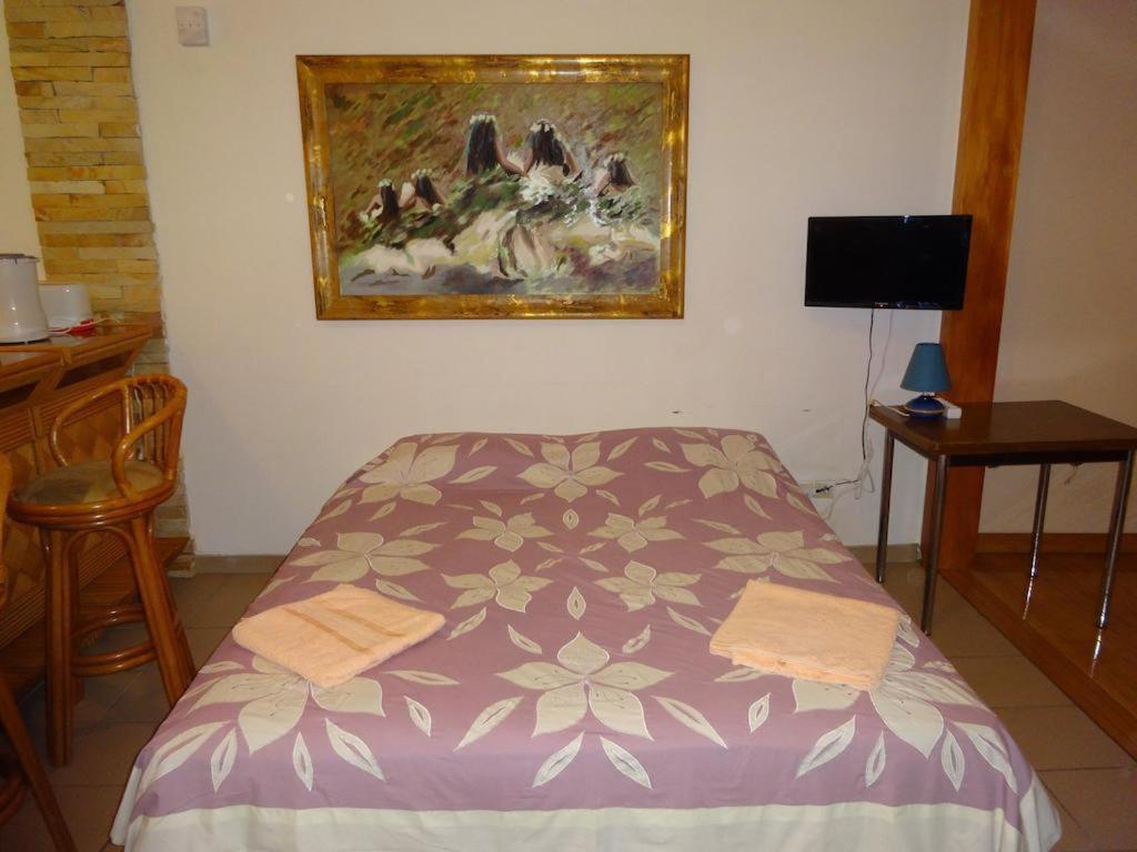 a bedroom with a bed with a painting on the wall at Fare Arearea Sweet Studio in Papeete