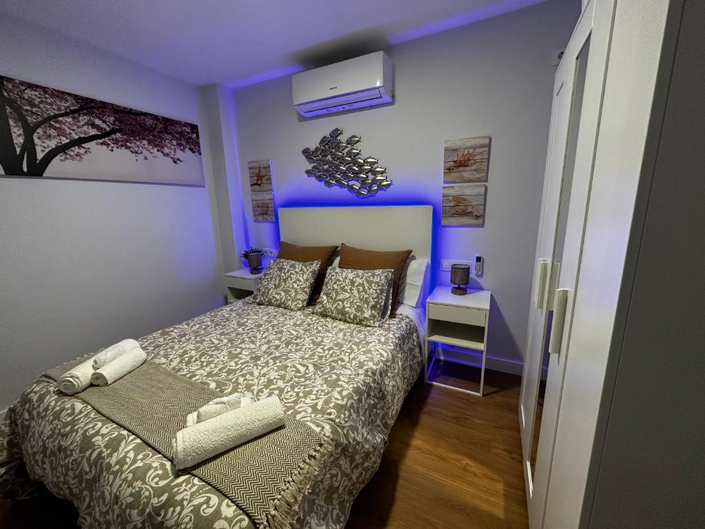 - une chambre avec un lit et une lumière bleue dans l'établissement PREMIUM - Dúplex Lujo Recién Reformado con Jardín, Piscina, Parking, Aire Acondicionado - Los Caños de Meca - 50m playa, à Los Caños de Meca