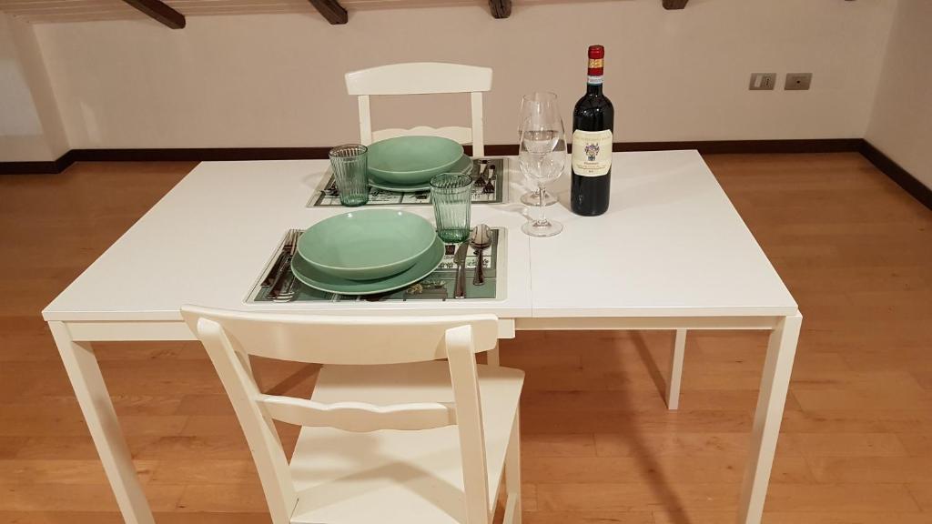 una mesa blanca con dos platos y una botella de vino en Vicino a Sant'Orsola e centro città, silenzioso e accogliente, en Bolonia