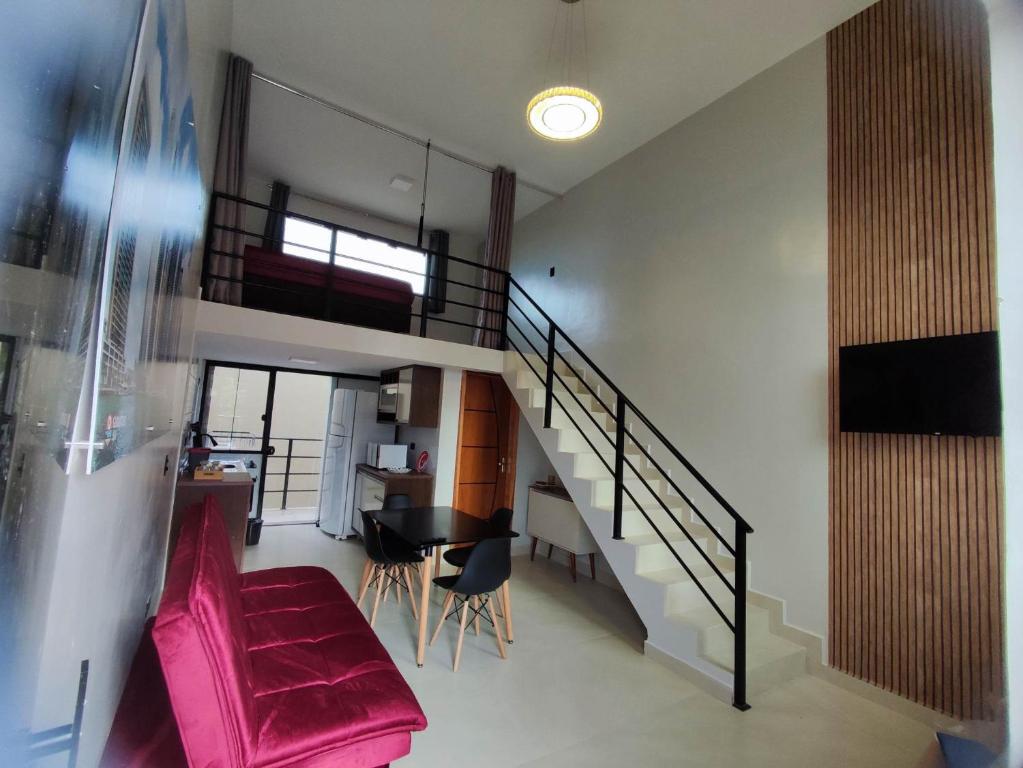 a living room with a staircase and a pink couch at GUARATUBA LOFTS in Guaratuba