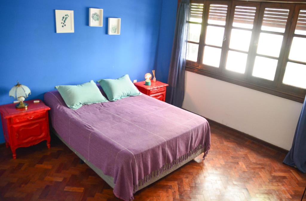 1 dormitorio con paredes azules y 1 cama con 2 mesas en Casabunda Multiespacio, habitación privada en el centro en Salta