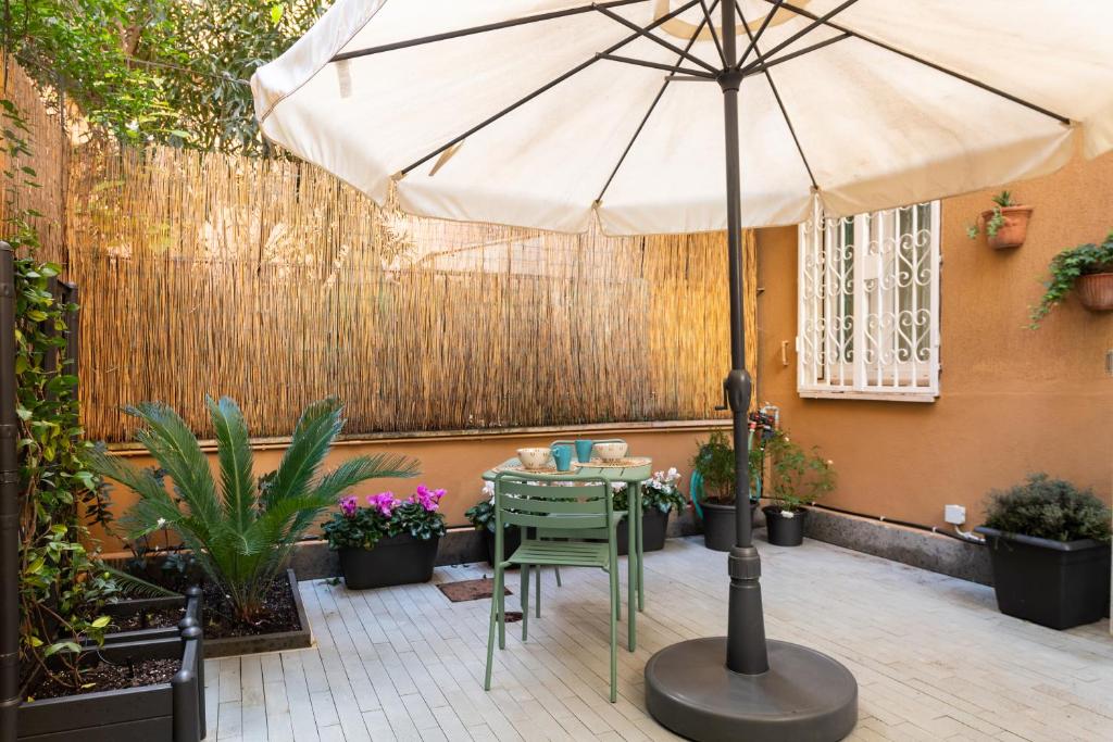 a table with an umbrella in a courtyard at Casa Vegezio Vaticano adiacente Metro Cipro nuovissimo con giardino privato self check-in in Rome