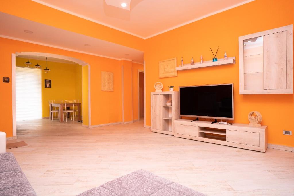 a living room with orange walls and a flat screen tv at Il Ciclamino in Tarquinia