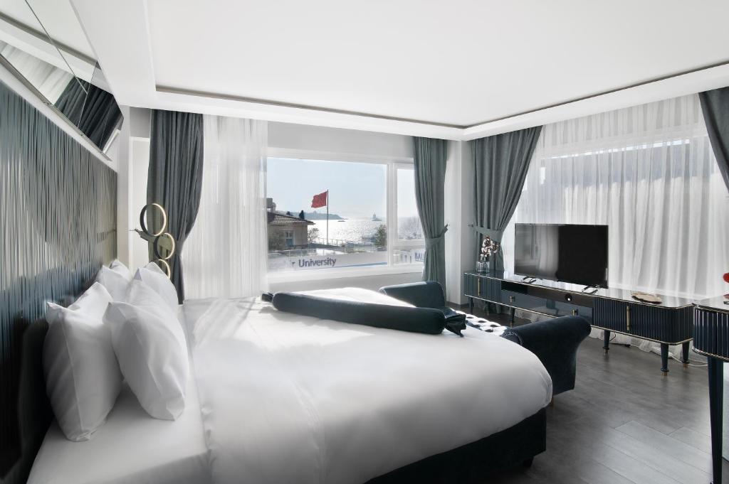 a bedroom with a large white bed and a television at Via Çırağan Hotel in Istanbul