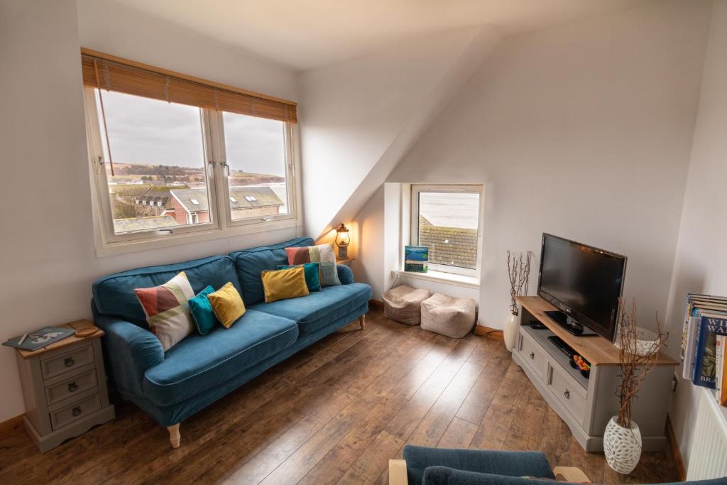 uma sala de estar com um sofá azul e uma televisão em Beach View Apartment em Stonehaven