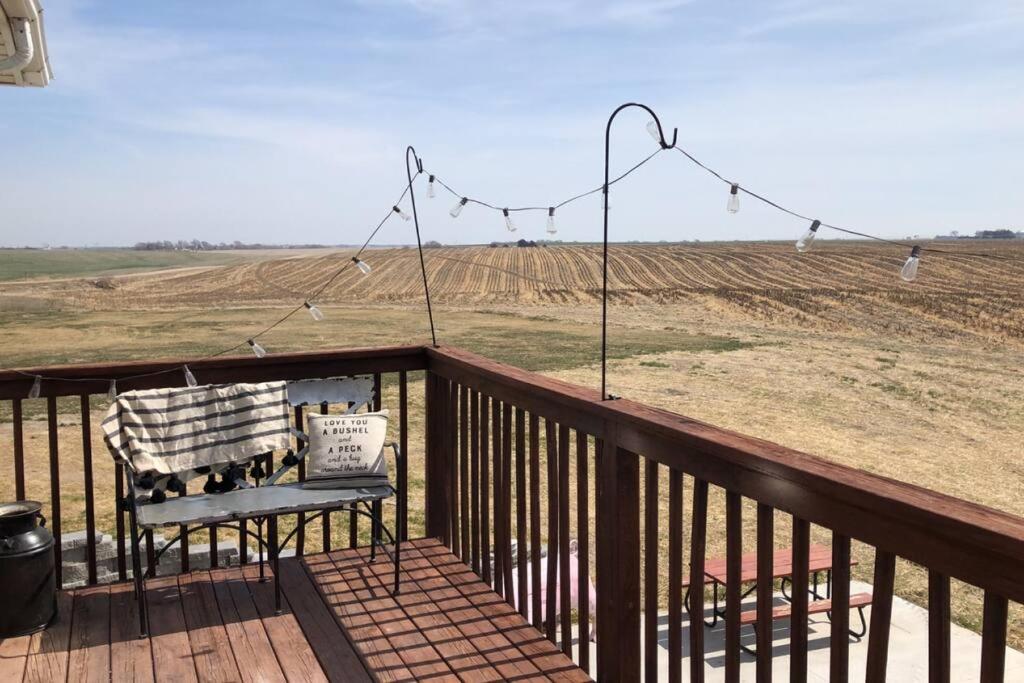 un banc sur une terrasse avec vue sur un champ dans l'établissement Breathtaking Rustic Farmhouse Getaway, à Seward