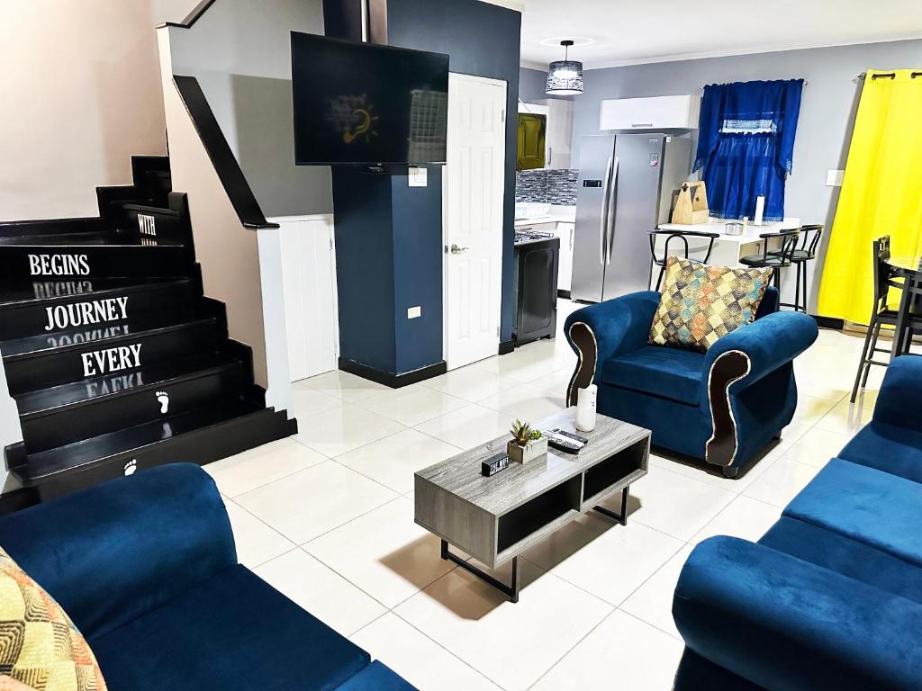 a living room with blue furniture and a kitchen at Luxury Crib 5 mins from the NMIA airport in Kingston
